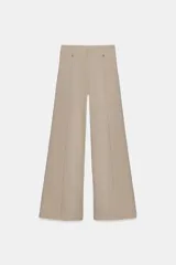 Jeans de tiro alto con corte wide leg y largo al tobillo. Presentan costuras verticales marcadas en el frente, cintura con trabillas y cierre frontal con cremallera, botón y gancho metálico.