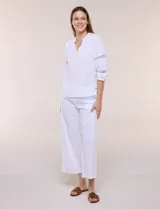 Pantalón crop de lino y algodón color blanco, con calce holgado, pierna ancha de corte recto y cintura elástica. Presenta bolsillos laterales y detalle de puntilla aplicada en el frente.