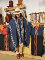 Poncho azul marino de hilo de algodón con diseño geométrico tejido en tonos beige y marrón claro, y flecos en los bordes.
