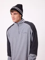 Gorro tipo beanie de punto en color gris, con franjas horizontales en verde y blanco, y logo de la marca Rusty en el frente.