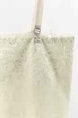 Top de punto color crema claro, corte recto y ajustado, con detalle de encaje floral bordado en el escote. Posee tirantes ajustables de color beige claro.