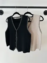 Chaleco tejido de punto color beige con corte sastrero, abotonadura frontal y detalle de bordado a mano en contraste a lo largo de los bordes.