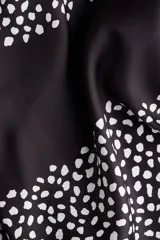 Top halter negro con estampado de lunares blancos, escote drapeado y espalda abierta con tiras anchas para anudar en la parte baja.