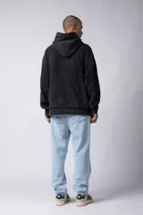 Buzo canguro de corte oversize, confeccionado en frisa de algodón con efecto de lavado gastado. Presenta un aplique decorativo cosido al corte en el centro del pecho, capucha amplia y bolsillo frontal tipo canguro.