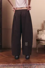 Pantalón de gabardina impermeable color marrón chocolate, con silueta amplia y relajada. Presenta cintura elastizada con pinzas delanteras que aportan volumen y movimiento a la prenda.