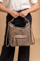 Cartera mochila color tostado, de cuero sintético, con compartimento principal amplio y bolsillos frontales con cierre. Tiene correas ajustables y asa superior para llevar al hombro o como mochila.