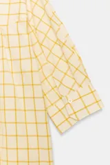 Vestido midi camisero de algodón, color amarillo con estampado a cuadros. Cuenta con cuello solapa, escote en V, mangas cortas con puño y bolsillos laterales ocultos en la costura, con diseño evasé.