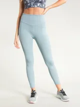 Calza deportiva de tiro alto con largo hasta el tobillo, confeccionada en tejido elástico de color celeste. Presenta un diseño minimalista con costura en V en la cintura y logo pequeño en la cadera.