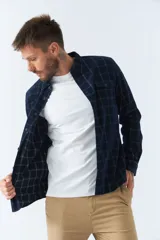 Camisa de pana a cuadros en tonos azul y bordó, de corte regular, manga larga, con cartera de botones y bolsillo frontal.