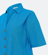 Camisa de manga corta confeccionada en mezcla de viscosa y lino color turquesa. Presenta cuello camisero con escote en V, bolsillos frontales de parche y cierre frontal con botones geométricos de efecto carey.
