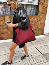 Bolso tote grande color bordó, con detalles en cuero negro en la base y las asas. Confeccionado en gabardina y forrado en tela Panamá.