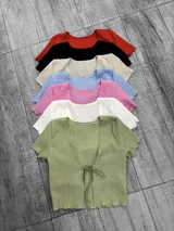 Blusa corta de tejido de punto acanalado, con escote redondo y mangas cortas. Se ata en el centro del frente con dos tiras del mismo tejido.