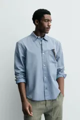 Camisa de corte relajado confeccionada en una mezcla de lyocell y algodón con efecto lavado. Presenta cuello solapa, manga larga con puños abotonados, bolsillo de plastrón en el pecho y cierre frontal con botones.