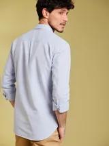 Camisa celeste a rayas verticales finas, de manga larga y corte clásico.