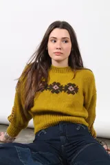 Sweater tejido de lana merino color mostaza, de corte boxy, con cuello redondo y diseño de flores bordadas en el pecho.