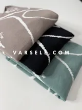 Sweater de tejido de punto con diseño abstracto de líneas blancas sobre fondo de color sólido. Presenta un corte clásico y textura suave.