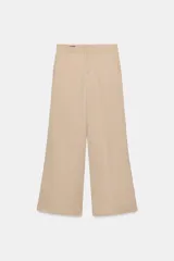 Pantalón de tiro alto color beige, estilo palazzo o ancho, confeccionado en mezcla de viscosa. Presenta bolsillos laterales y cierre frontal con cremallera y botón.