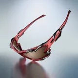 Lentes de sol con montura envolvente color rojo mate y detalles metálicos de líneas orgánicas. Cuentan con lentes de nylon color marrón con protección UV400 categoría 3.