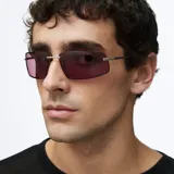 Lentes de sol con montura rectangular envolvente de acero inoxidable color plata y lentes de nylon color violeta. Presentan patillas de acetato y diseño inspirado en la estética de los años 2000.