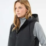 Chaleco largo tipo puffer en color negro, con diseño acolchado, cierre frontal completo y capucha ajustable con cordones. Cuenta con bolsillos laterales y un corte recto hasta la rodilla.