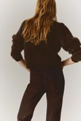 Jean de corte bootcut y tiro alto en color marrón oscuro, con diseño de cinco bolsillos y raya marcada en el frente y la espalda.
