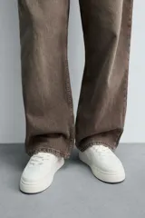 Zapatillas deportivas de estilo retro, color beige y marrón, con cordones y suela gruesa.