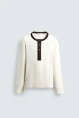 Camiseta de manga larga en tejido de punto canalé color crudo, con cuello redondo y tapeta frontal con botones en color marrón oscuro a contraste.