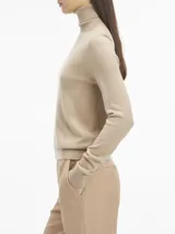 Sweater color beige de tejido de punto, con cuello alto y mangas largas.