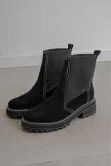 Botas de caña media confeccionadas en gamuza y neopreno, con suela track de goma y costuras a la vista en color blanco.