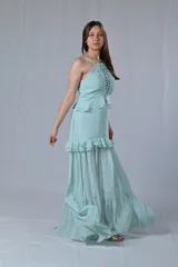 Conjunto de dos piezas compuesto por un top de tirantes finos con detalle de tejido trenzado en el frente y una falda larga con volados en capas, confeccionado en tela fluida.