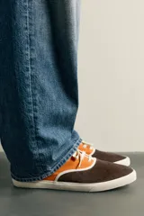 Zapatilla casual de hombre con diseño combinado en color naranja y marrón oscuro, con cordones y suela de goma en contraste.