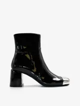 Bota corta negra de charol con puntera metálica plateada, caña media, cierre lateral con cremallera y tacón cuadrado.