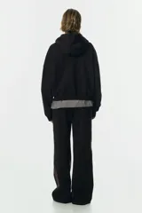 Campera con capucha de corte holgado, confeccionada en felpa con interior cepillado. Presenta hombros caídos, cierre frontal, bolsillos tipo parche y terminaciones en punto acanalado en puños y bajo.