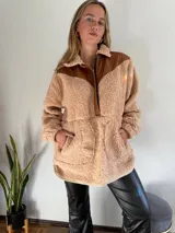 Canguro beige de corderito con detalles en cuero marrón en cuello, hombros y cierre.