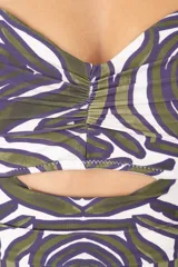 Traje de baño enterizo tipo bandeau con escote strapless, diseño con pliegues horizontales en el frente y estampado geométrico orgánico en tonos verdes y púrpuras.
