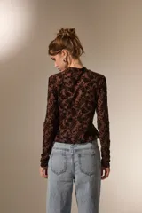 Top de manga larga con cuello alto, confeccionado en tejido semitransparente con estampado tipo paisley en relieve.