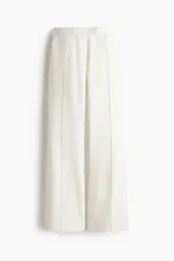 Pantalón sastrero blanco de pernera ancha y recta, con pliegues frontales marcados.
