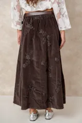 Pollera larga de pana color chocolate, con diseño de tablas frontales y bordados florales en toda la superficie. Cuenta con cintura con pasacintos.