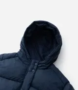 Campera puffer acolchada color azul marino, con capucha, cierre frontal con broches a presión, bolsillos laterales y cordón regulador en la cintura para ajuste entallado.