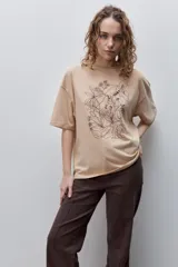 Remera negra de silueta amplia y calce relajado, con cuello redondo, mangas cortas con hombros caídos y estampa botánica en líneas blancas en el frente.