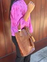 Matera de cuero con textura de cocodrilo en color tostado, con asas cortas y detalle de borla decorativa lateral.