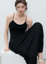 Vestido largo de punto fino color negro, con diseño recto, cuello escotado y tirantes finos que se cruzan en la espalda.