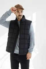 Chaleco acolchado negro con cierre frontal, cuello alto y bolsillos laterales con cierre.