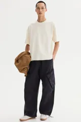 Remera de algodón en punto liviano color beige, con diseño boxy de hombros caídos, cuello redondo con ribete acanalado y corte oversized.