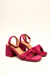 Sandalia de tacón cuadrado medio, confeccionada en terciopelo negro. Presenta un diseño de tiras cruzadas con nudo en la parte delantera y una tira ajustable con hebilla en el tobillo.