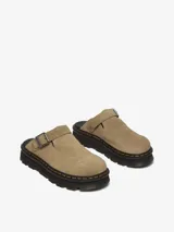 Mule Dr. Martens modelo Zebzag, color beige, confeccionado en gamuza. Presenta una correa ajustable con hebilla metálica, suela híbrida con cámara de aire en EVA y PVC, y las icónicas costuras amarillas de la marca.
