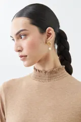 Remera de punto color tostado melange, con cuello alto con volados y mangas largas.