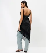 Vestido midi negro de poliuretano, con breteles finos regulables, escote en V y ruedo asimétrico adornados con encaje.