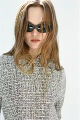 Chaqueta cruzada de estructura en tejido tweed de mezcla de hilos en tonos blanco y negro, con escote en pico, manga larga y cierre frontal con botones a presión ocultos.