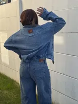 Campera de jean con diseño semi oversized, cuenta con bolsillos frontales y elástico en la espalda para un ajuste cómodo en la cintura.
